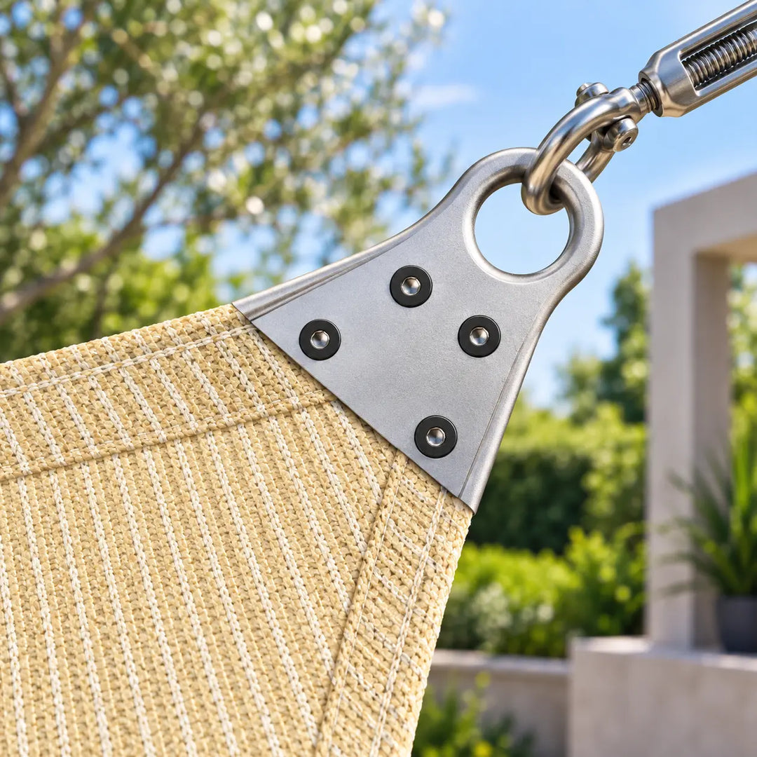 Close-up of a beige woven patio hammock corner with a silver metal hanger and swivel, shown outdoors against a blurred green garden background.